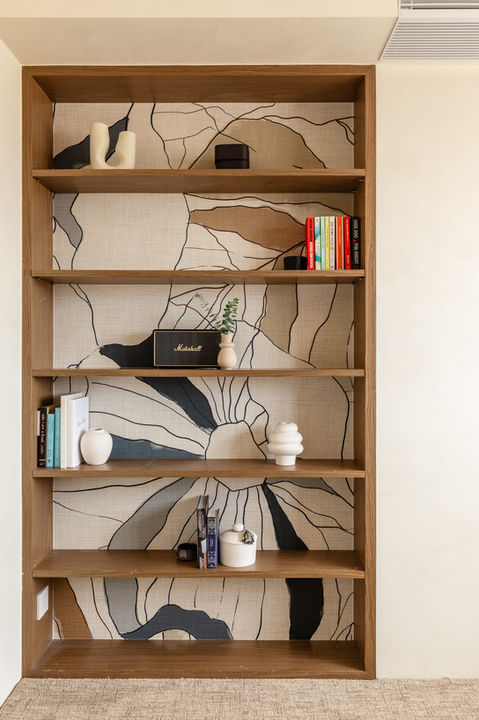 Contemporary wooden bookshelf with artistic wallpaper backdrop, showcasing modern home decor elements and books. Perfectly styled for a minimalist living room design. Ideal for interiors focusing on elegance and functionality.
