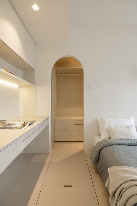 Minimalist bedroom design by MAD Studio featuring modern white cabinetry, an arched doorway, and elegant bedding. Perfect for contemporary home interiors, small space solutions, and minimalist decor enthusiasts.