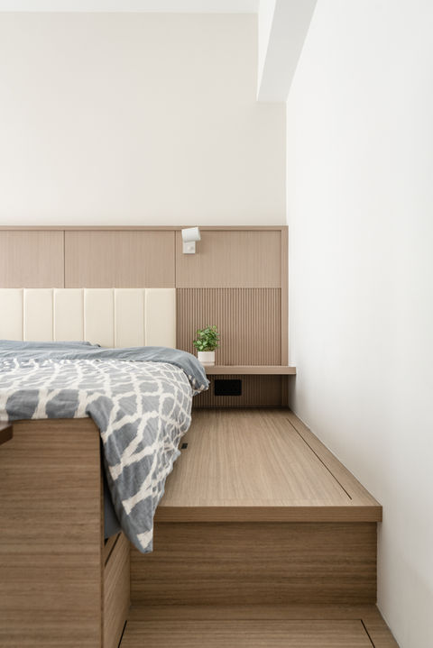 Modern minimalist bedroom design with light wood flooring and headboard, featuring a cozy bed adorned with a neutral patterned duvet. A small green plant on a floating nightstand complements the serene color palette. Ideal for small spaces, this contemporary interior showcases clean lines and functionality. Perfect for home decor inspiration and interior design trends.