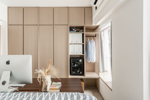 Modern minimalist home office interior with sleek wooden cabinetry and a built-in wardrobe, featuring a stylish iMac setup. Natural light filters through large windows, highlighting the cozy and functional design. Perfect for optimizing small space living.