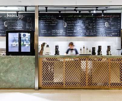 Modern juice bar interior featuring a sleek marble counter paired with a stylish wooden lattice design. The chic blackboard menu adds an urban touch, with industrial lighting illuminating the open space. Ideal for showcasing contemporary interior design trends and innovative cafe aesthetics. Commercial interior design
