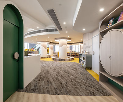 Modern library interior design featuring a spacious open layout with elegant architectural details. The design includes a blend of contemporary and inviting elements, including stylish circular bookshelves and soft ambient lighting. A combination of carpet and wood flooring enhances warmth and sophistication, ideal for public spaces and reading areas. Commercial Interior Design